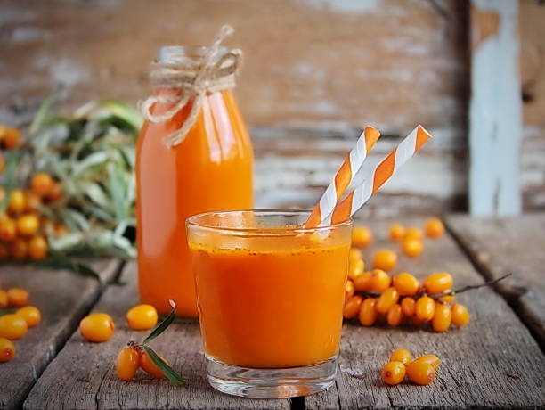 Homemade buckthorn soft drink in a glass and ripe sea buckthorn berries on the table. Healthy and diet food